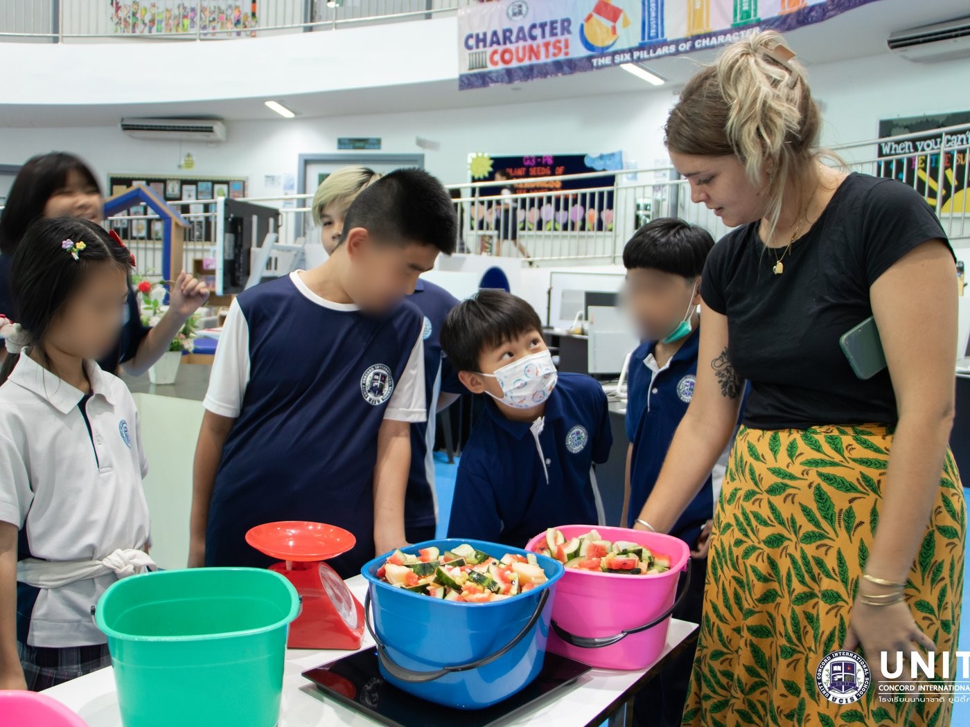 Students weighing cafeteria food waste on a scale to track and graph compost data