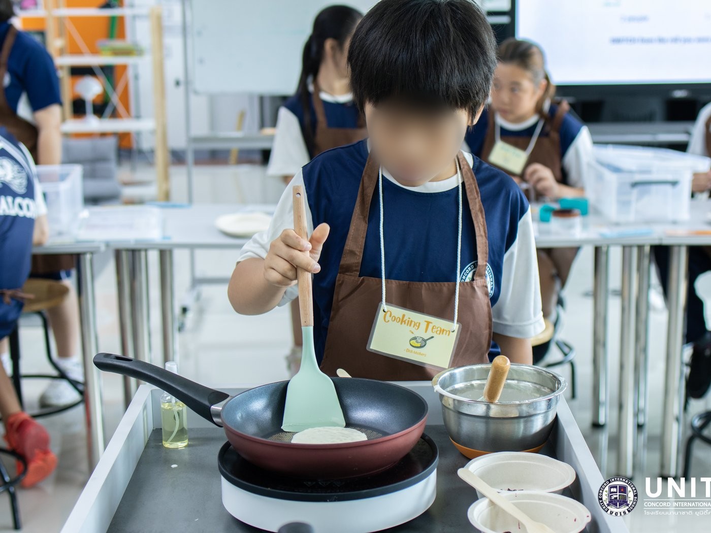 A student on the Cooking Team pouring batter into a pan to cook a test pancake