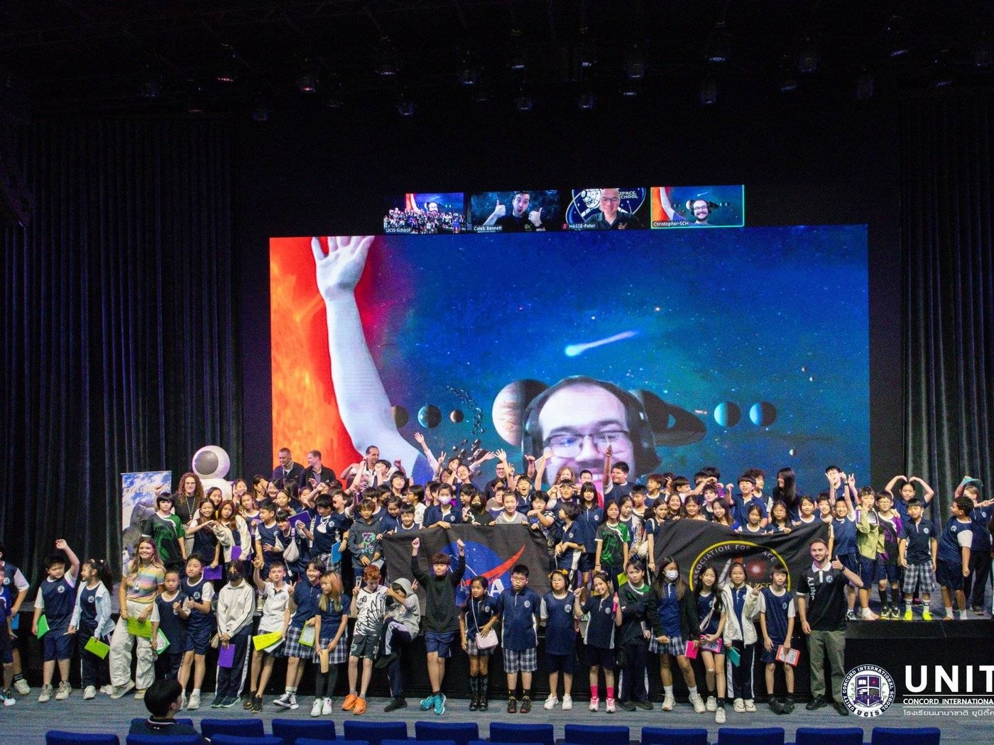 The whole grade posed on stage with NASA and HASSE banners after their space school video call