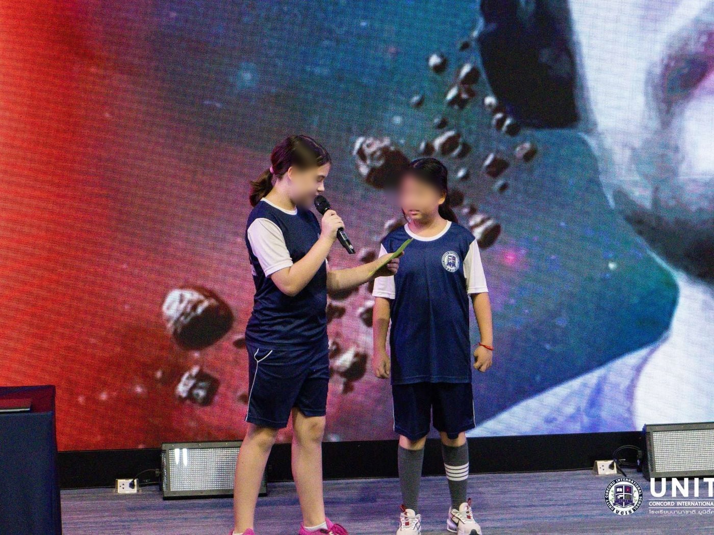 Two students on stage sharing the microphone during the space school Q&A