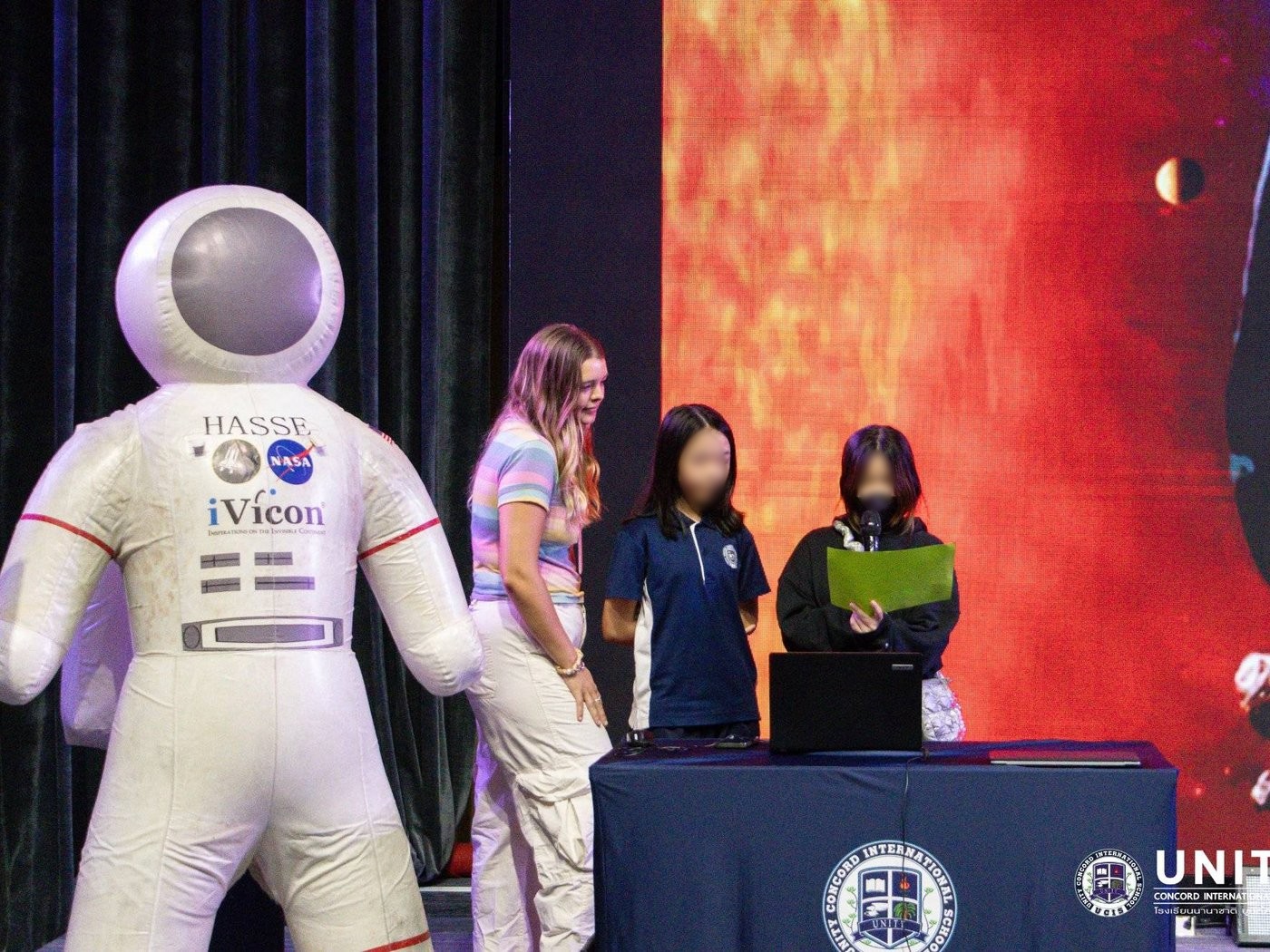 Students at a laptop next to the HASSE astronaut mascot, preparing questions for the NASA scientist interview