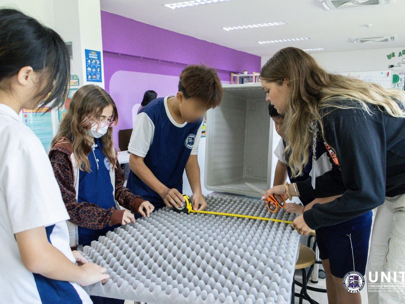 Students measuring and cutting acoustic foam panels to build their own podcast soundbooth