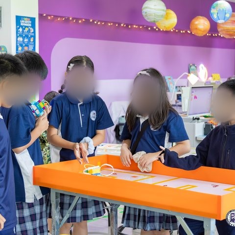 Students testing a LEGO SPIKE robot on a sumo-style challenge table