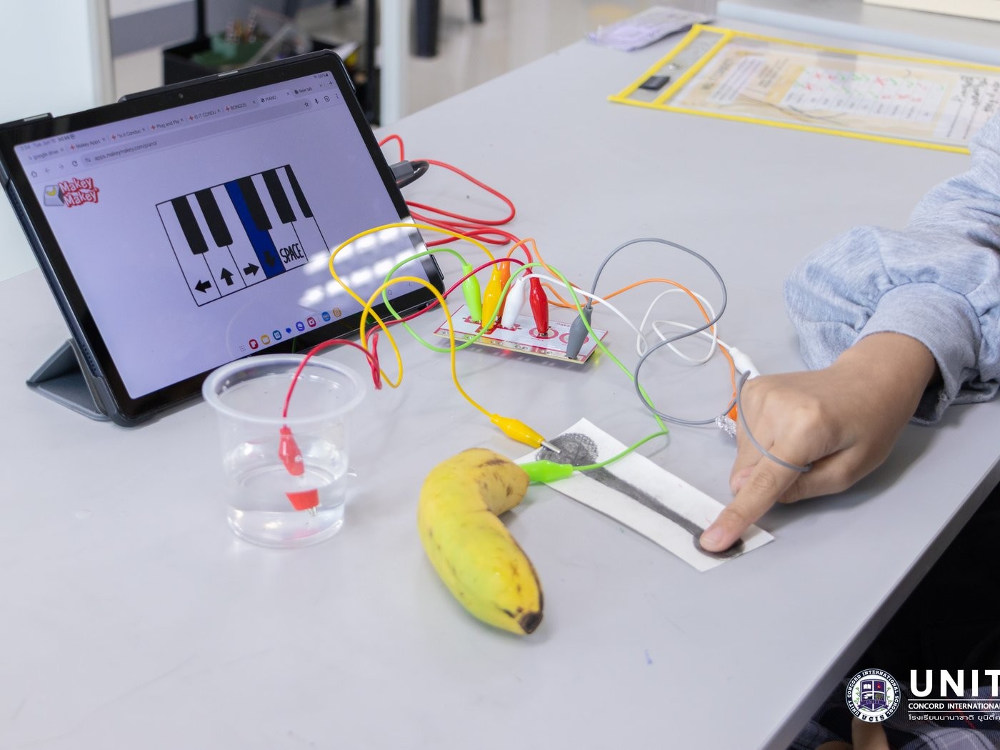 A Makey Makey piano circuit wired through a banana and a cup of water