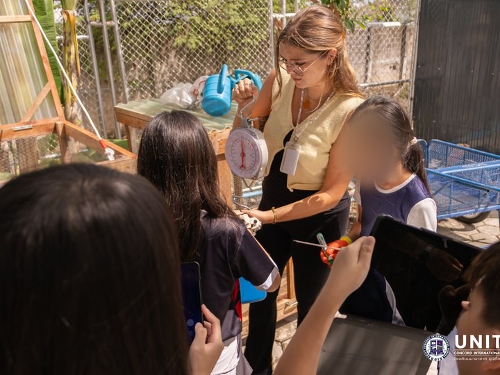 Claire weighing compost with students in the school garden